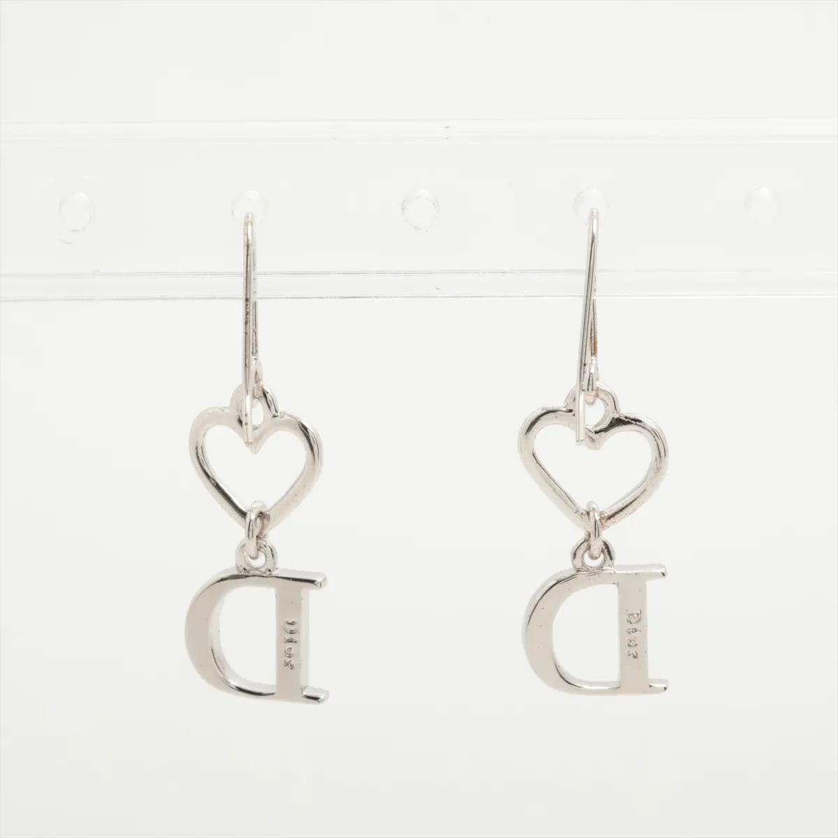 D logo earrings (for both ears), metal and rhinestone, silver. Shows wear, tarnishing, and dirt. — view 2
