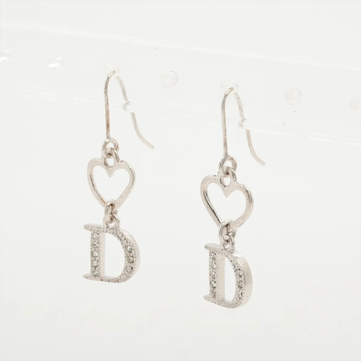 D logo earrings (for both ears), metal and rhinestone, silver. Shows wear, tarnishing, and dirt. — view 3