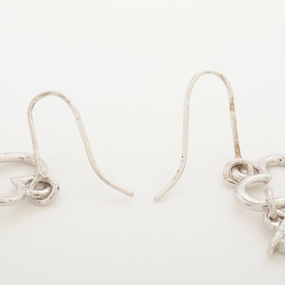 D logo earrings (for both ears), metal and rhinestone, silver. Shows wear, tarnishing, and dirt. — view 4