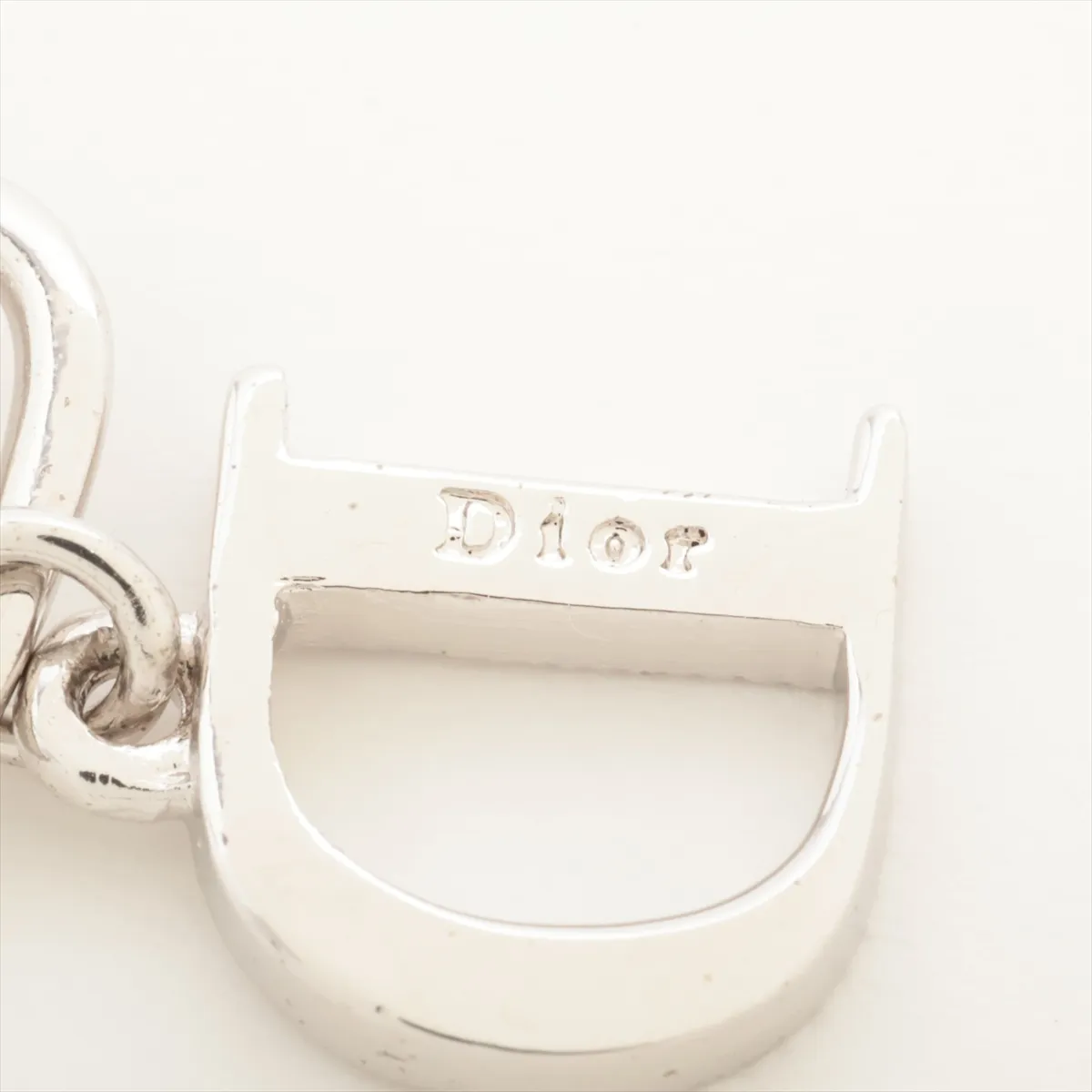 D logo earrings (for both ears), metal and rhinestone, silver. Shows wear, tarnishing, and dirt. — view 5