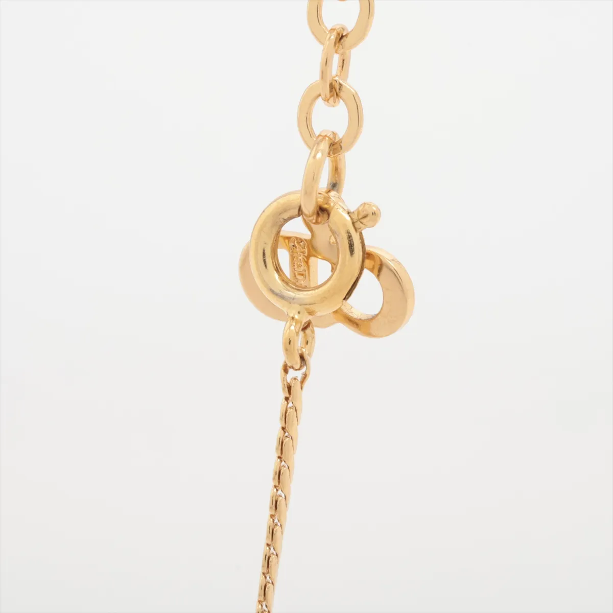 CD logo necklace, gold-plated with rhinestones. Shows wear, tarnishing, and discoloration. — view 3