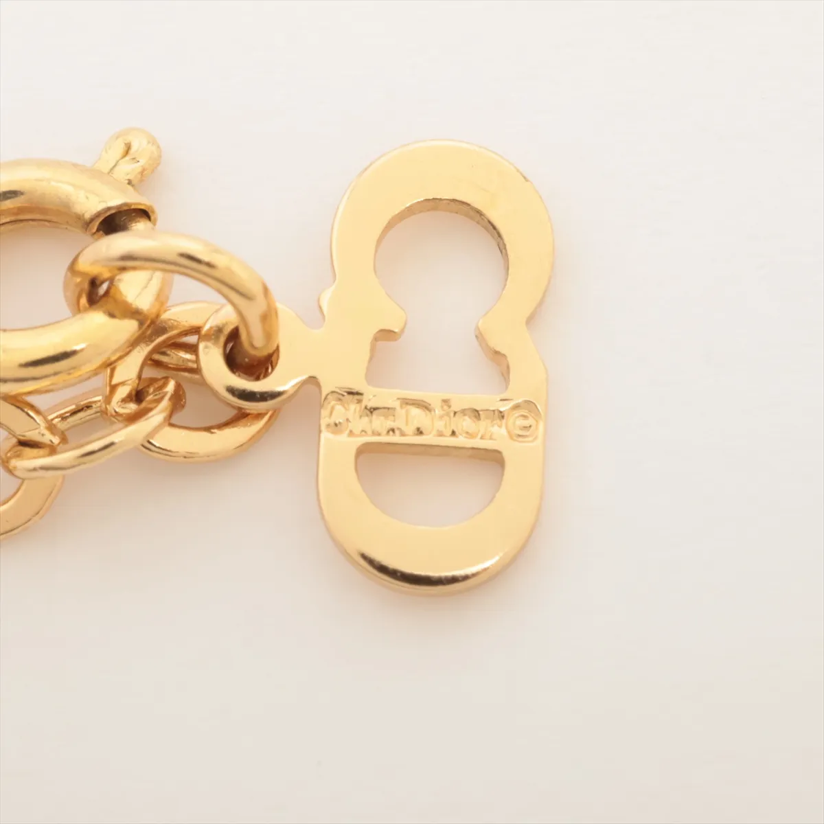 CD logo necklace, gold-plated with rhinestones. Shows wear, tarnishing, and discoloration. — view 4