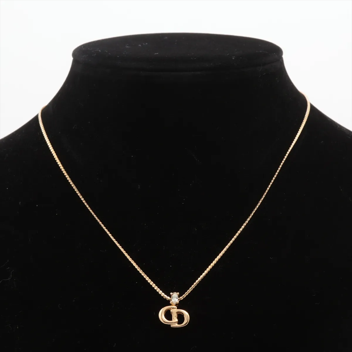 CD logo necklace, gold-plated with rhinestones. Shows wear, tarnishing, and discoloration. — view 5