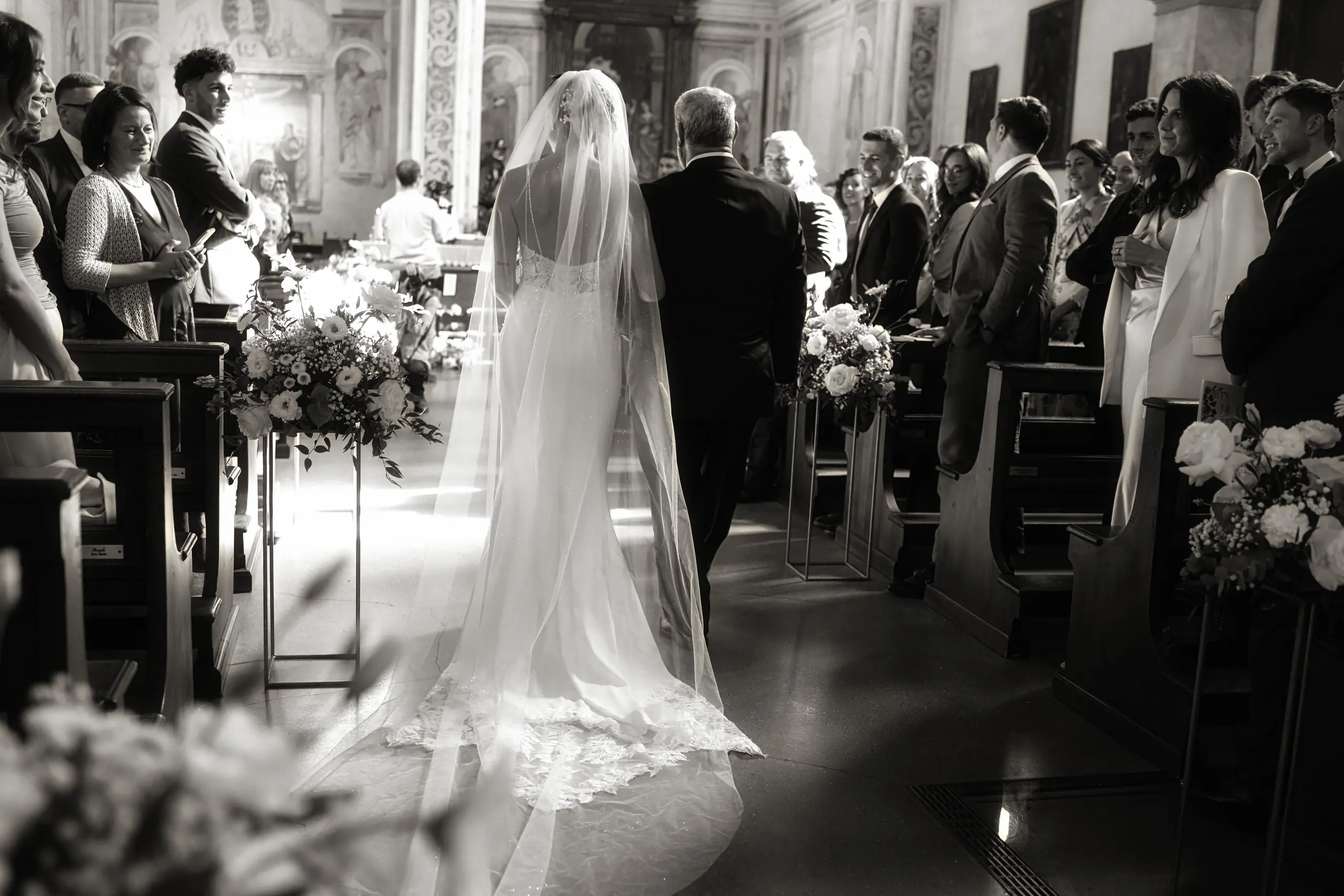 Ingresso della sposa in chiesa al braccio del papà, fotografia di matrimonio in bianco e nero
