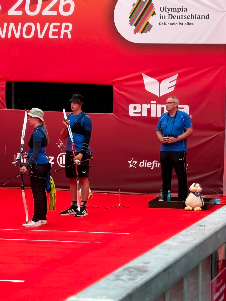 Miriam Wiebel und Oskar Mühl warten mit ihren Recurvebogen in der Finalarena der Finals 2026 in Hannover.