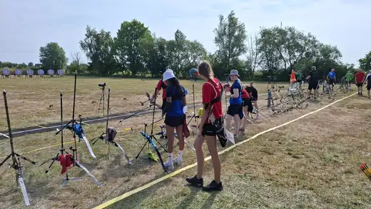 Schützen stehen an einer Reihe von Bogensportgeräten, bereit für die Landesmeisterschaft WA im Freien.
