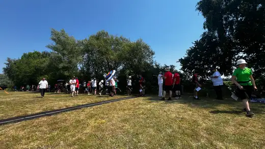 Teilnehmer und Betreuer versammeln sich auf einer Wiese unter blauem Himmel bei der Landesmeisterschaft WA im Freien.