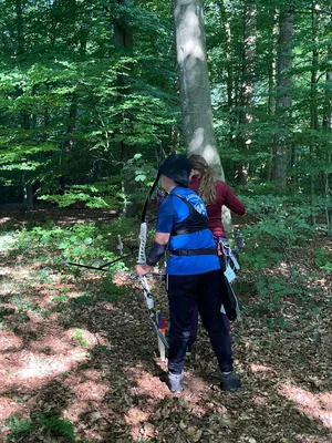 Schützin steht mit ihrem Recurvebogen an einer Station im Waldparcours