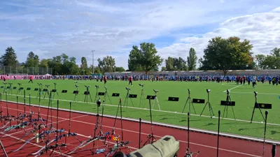 Panorama des grünen Wettkampffelds mit Bögen, Spektiven und der Scheibenreihe im Hintergrund.
