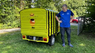 Ein Vereinsmitglied steht neben dem gelben Kleintransporter mit schwarz-gelben Streifen auf dem Bogenplatz.