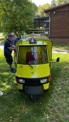 Frontansicht des gelben Kleintransporters mit einem großen Pfeil über dem Dach auf dem Bogenplatz.