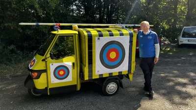 Ein Vereinsmitglied im blauen Shirt steht neben dem fertig geschmückten gelben Kleintransporter.