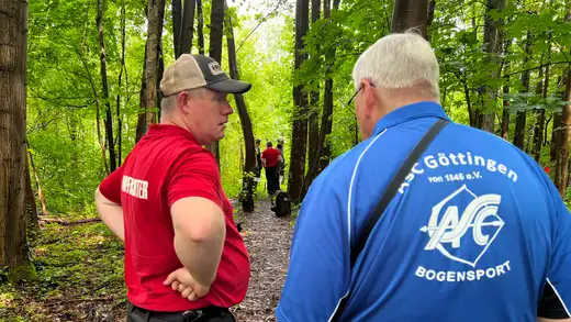 Zwei Schützen im Vordergrund, im Hintergrund weitere Teilnehmer auf einem Waldweg bei der Landesmeisterschaft Feldbogen.
