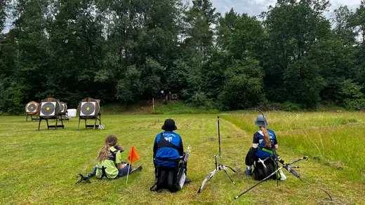 Drei Bogenschützen sitzen im Gras und warten auf ihren Start bei der Landesmeisterschaft Feldbogen 2026 in Wolfsburg.