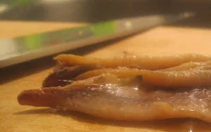 Acciughe salate condite con prezzemolo e peperoncino su piatto di ceramica siciliana