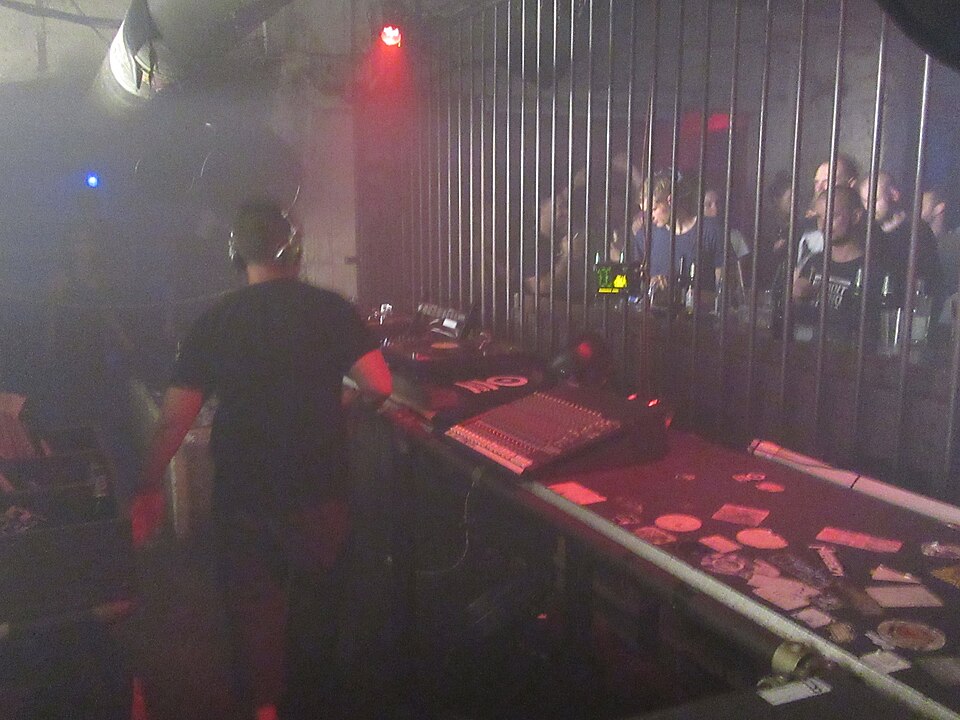 A DJ performing inside Tresor in Berlin with the booth lit against the dark club interior.