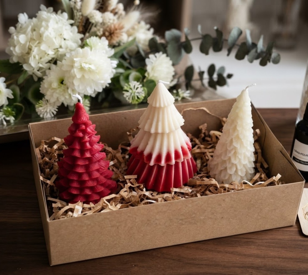 Three Christmas-tree-shaped scented candles: red, ombre and white