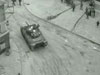 Sherman tanks driving through a small French village.
