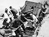 Dragging a gun up a sand dune.