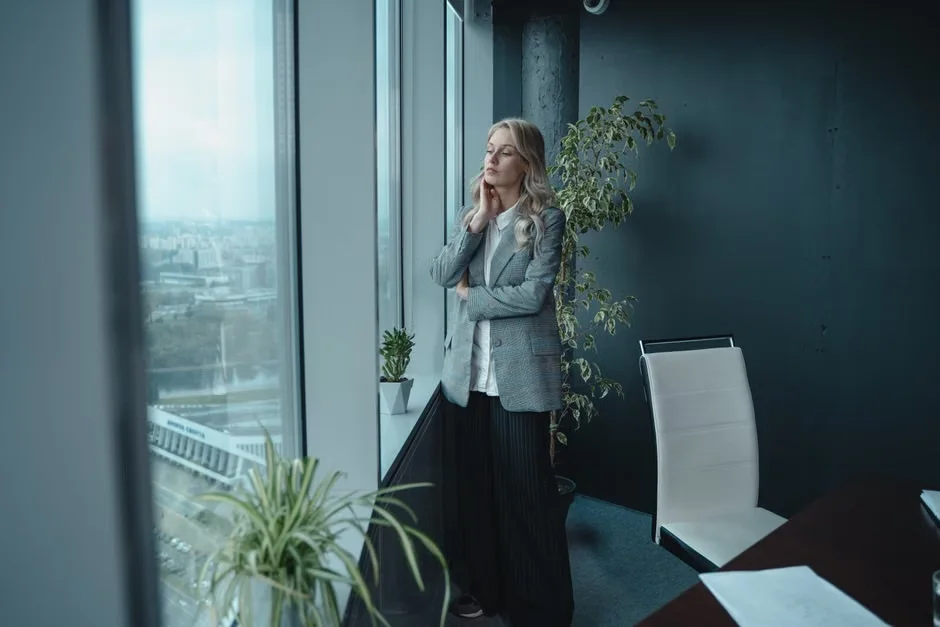 Woman standing at a window with her eyes closed
