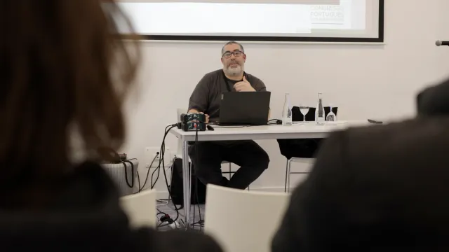 Orador durante uma sessão, com a apresentação do congresso projetada ao fundo