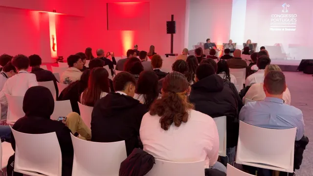 Plateia a assistir a um painel de debate, com o mote «Formar e Inovar» projetado no palco