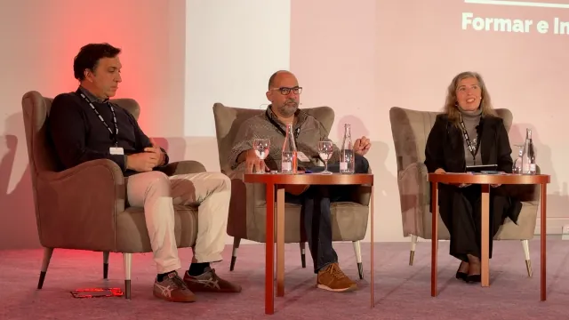 Painel de debate com três oradores em palco, sob o mote «Formar e Inovar»