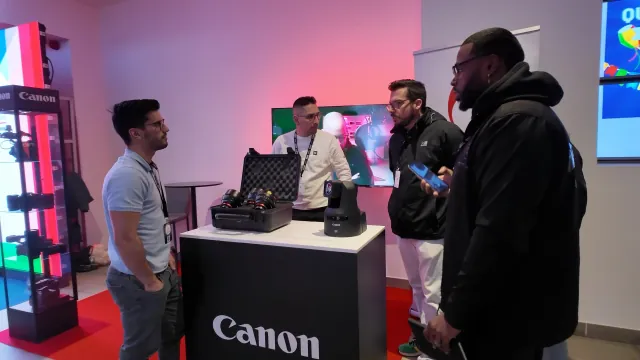 Visitantes no stand da Canon, à volta de uma câmara PTZ e de um conjunto de lentes