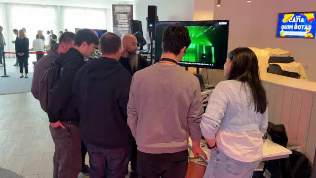 Grupo a assistir a uma demonstração de iluminação no stand, com projeção de um espetáculo