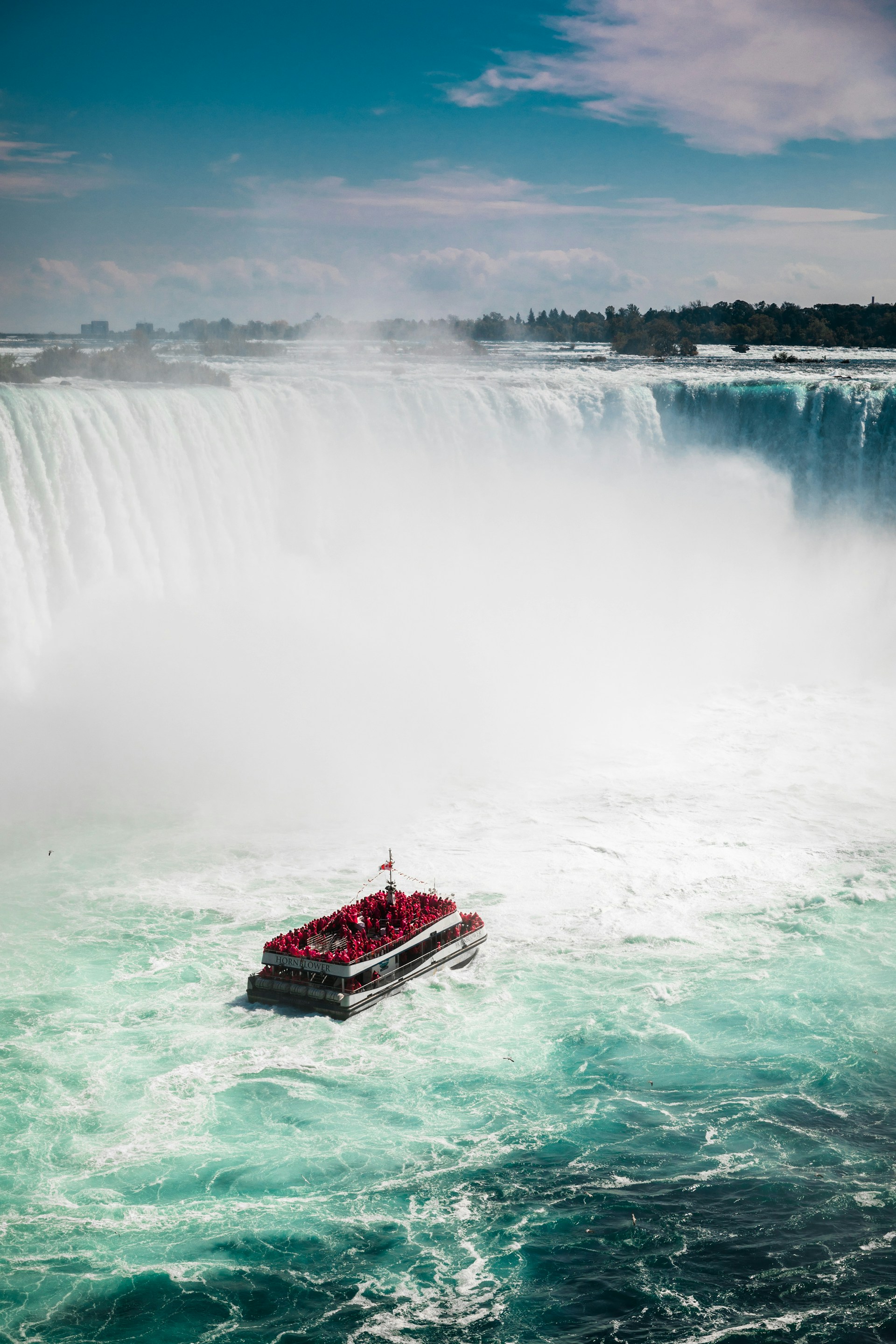 Paseo en barco por las Cataratas del Niágara con gente observando desde el mirador