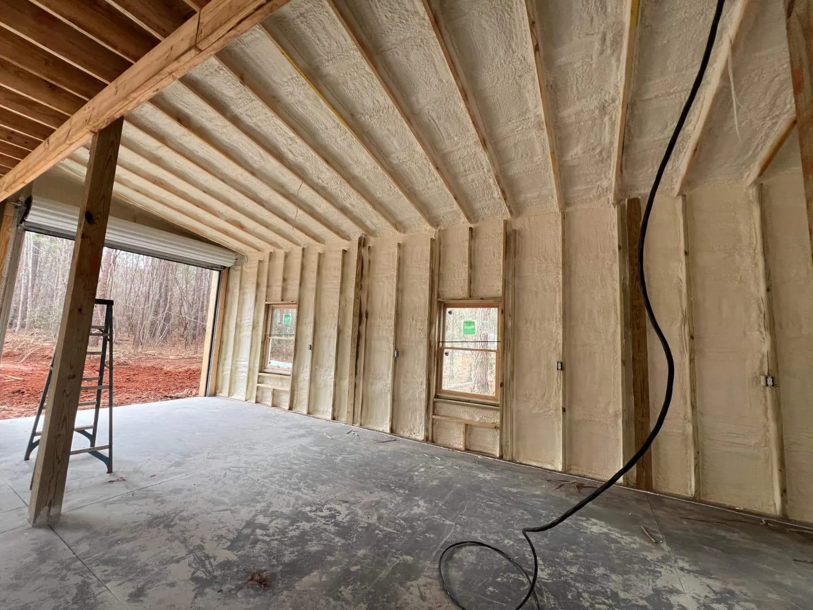 Spray foam insulation on the roofline and walls of a home with wooded views