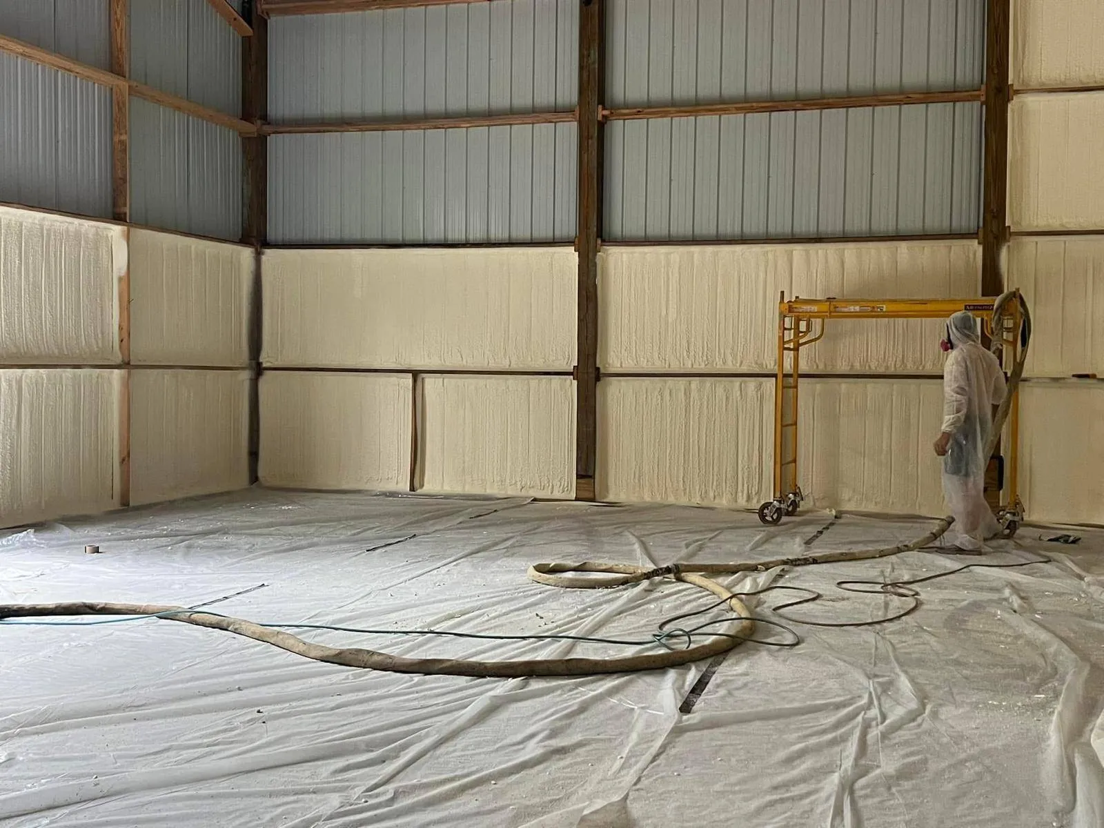 Installer spraying closed-cell foam on the walls of a pole barn
