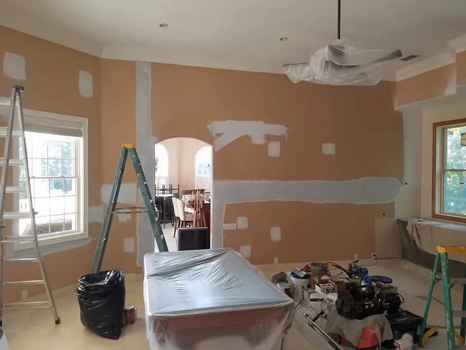 Room with fresh drywall patches and ladders during a repair and repaint