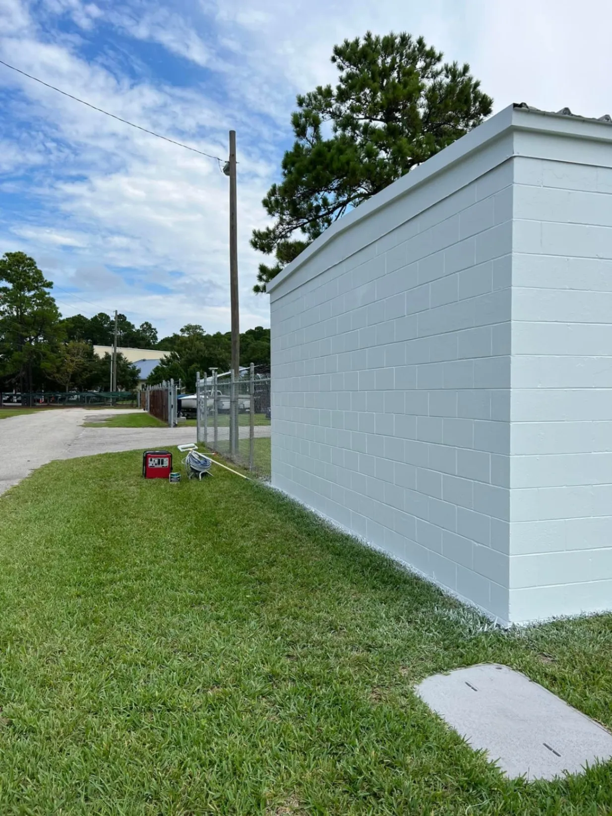 Long commercial block wall freshly painted white beside a lawn