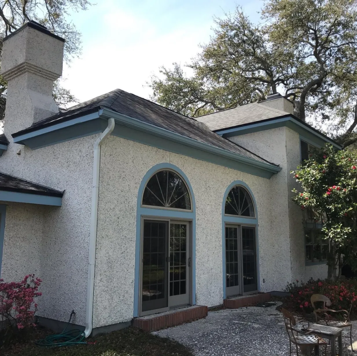 Stucco home with arched windows and gray trim after an exterior repaint