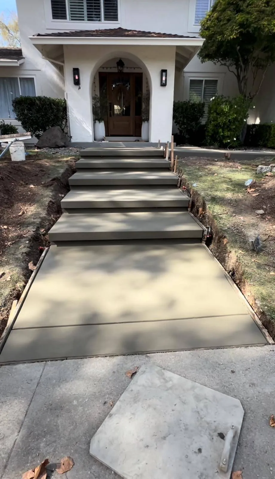 New concrete entry steps and front walkway leading to a white stucco home