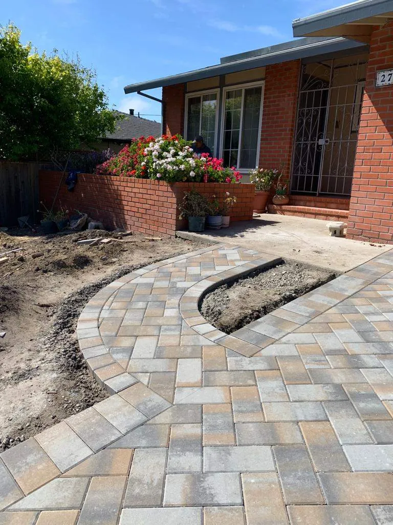 Curved paver walkway and border leading to a brick home's entry
