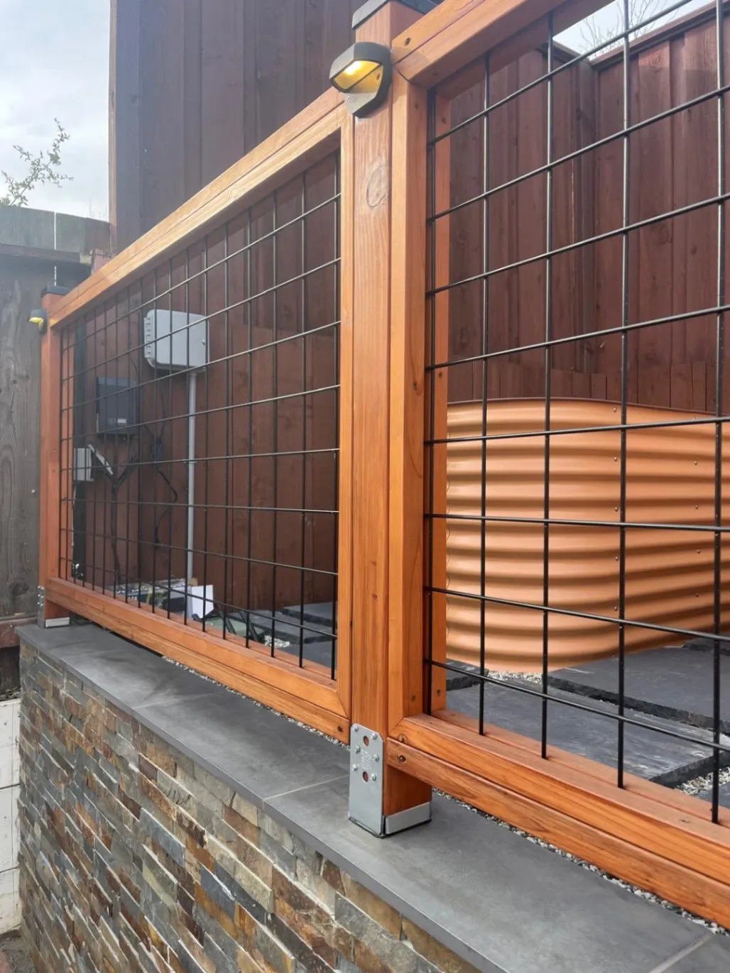 Wood and wire trellis mounted on a stacked-stone veneer wall