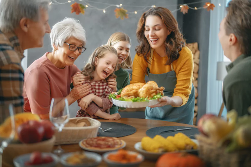 Mother serving roasted turkey at a Thanksgiving table surrounded by her extended family, emphasizing pregnancy-safe Thanksgiving ideas.