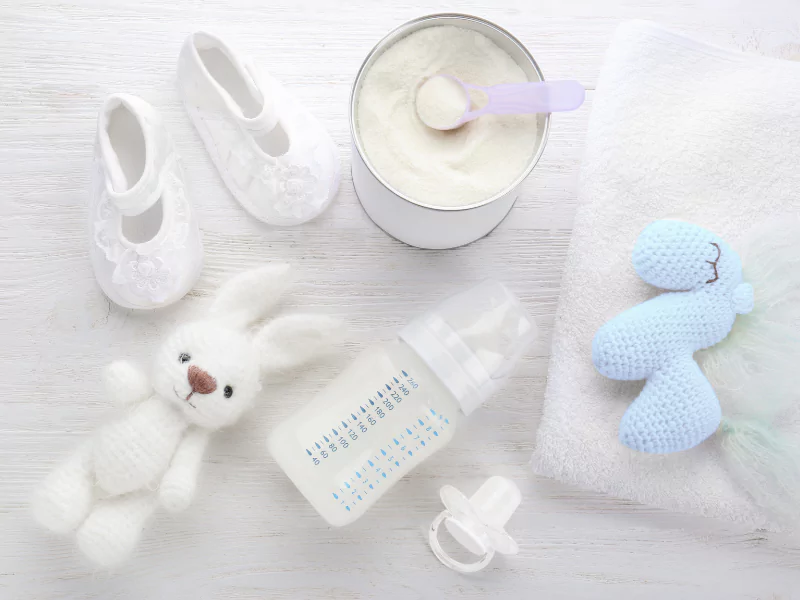 Cozy newborn essentials including knitted hat, tiny shoes, and soft blanket by a crib—perfect for a baby’s magical homecoming.