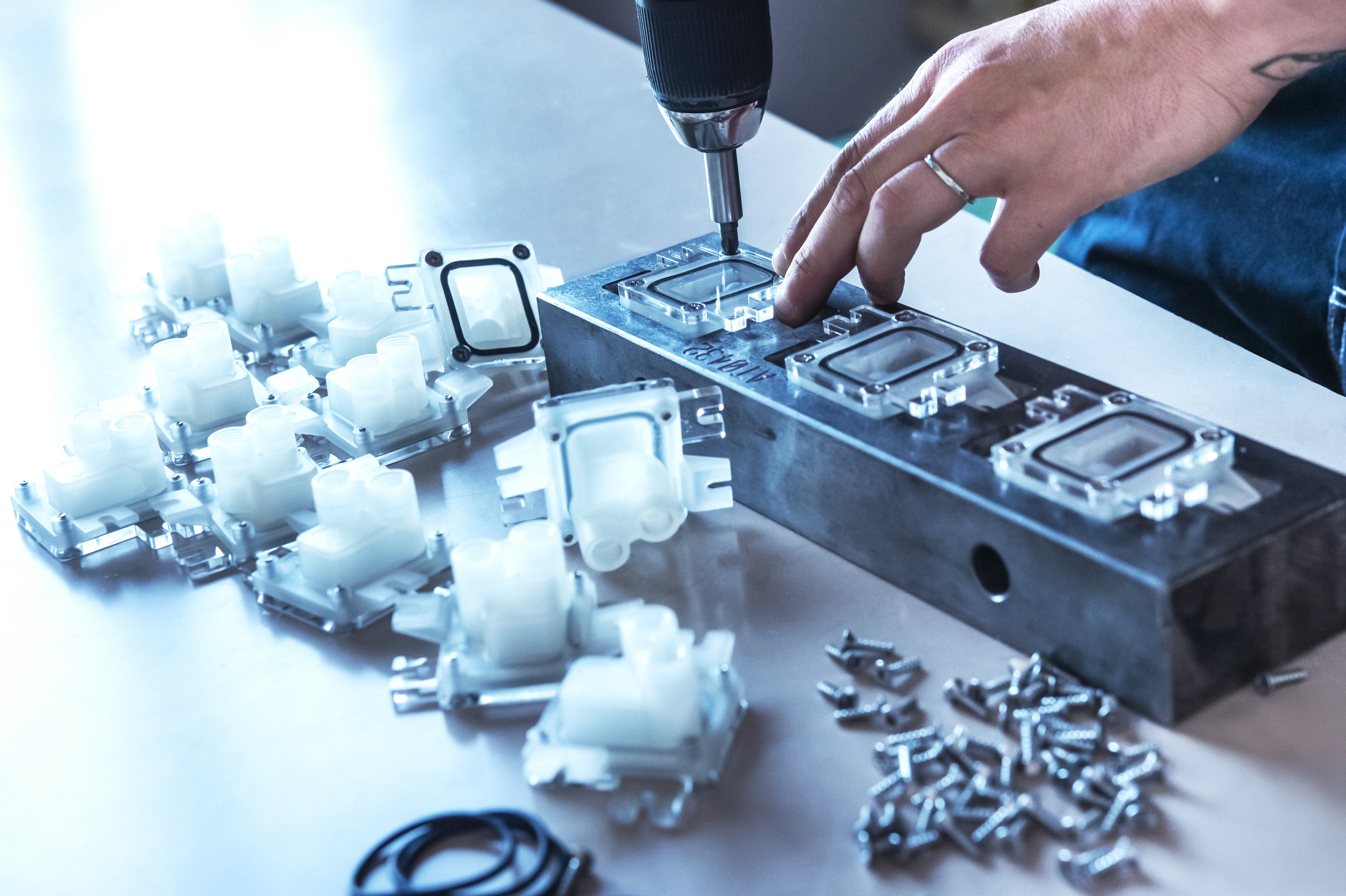 Foto che ritrae mani di un operatore mentre avvita dei componenti plastici allo stampo