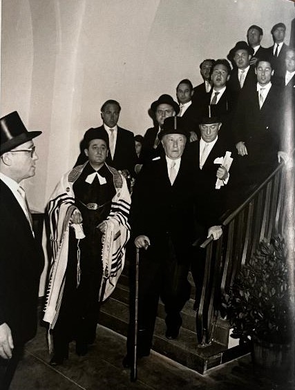 The photograph shows the inauguration of the Cologne synagogue in 1959 together with Federal Chancellor Konrad Adenauer. Also visible is Rabbi Hermann Helfgott, later known as Zvi Asaria, a former Jewish prisoner of war from Oflag VI C in Osnabrück. After the horrors of World War II, he dedicated his life to rebuilding Jewish life in Germany and promoting reconciliation and dialogue.