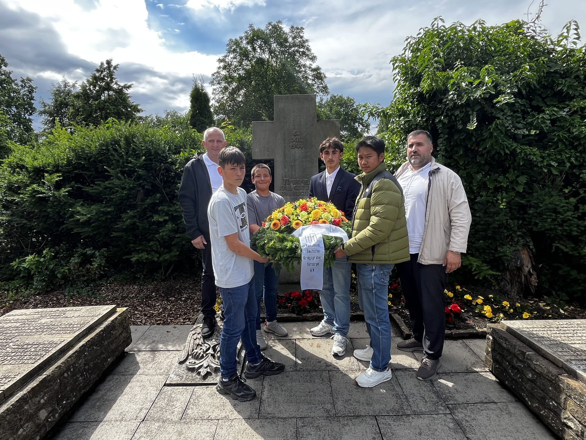 Nachkommen von Arso Čurović und Đorđe Ničota legen gemeinsam mit deutschen Schülern einen Kranz am Gedenkkreuz für die Opfer des 6. Dezember 1944 auf dem Friedhof Eversburg in Osnabrück nieder (Foto: Privatarchiv)