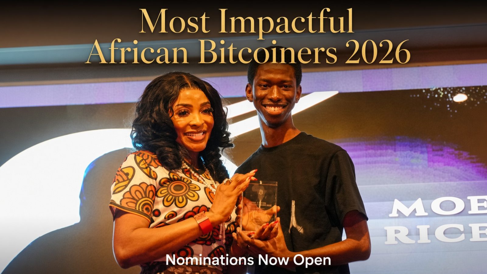 Dr. Nabila Fash presents a crystal award to Abubakar Nur Khalil at the Most Impactful African Bitcoiners ceremony.