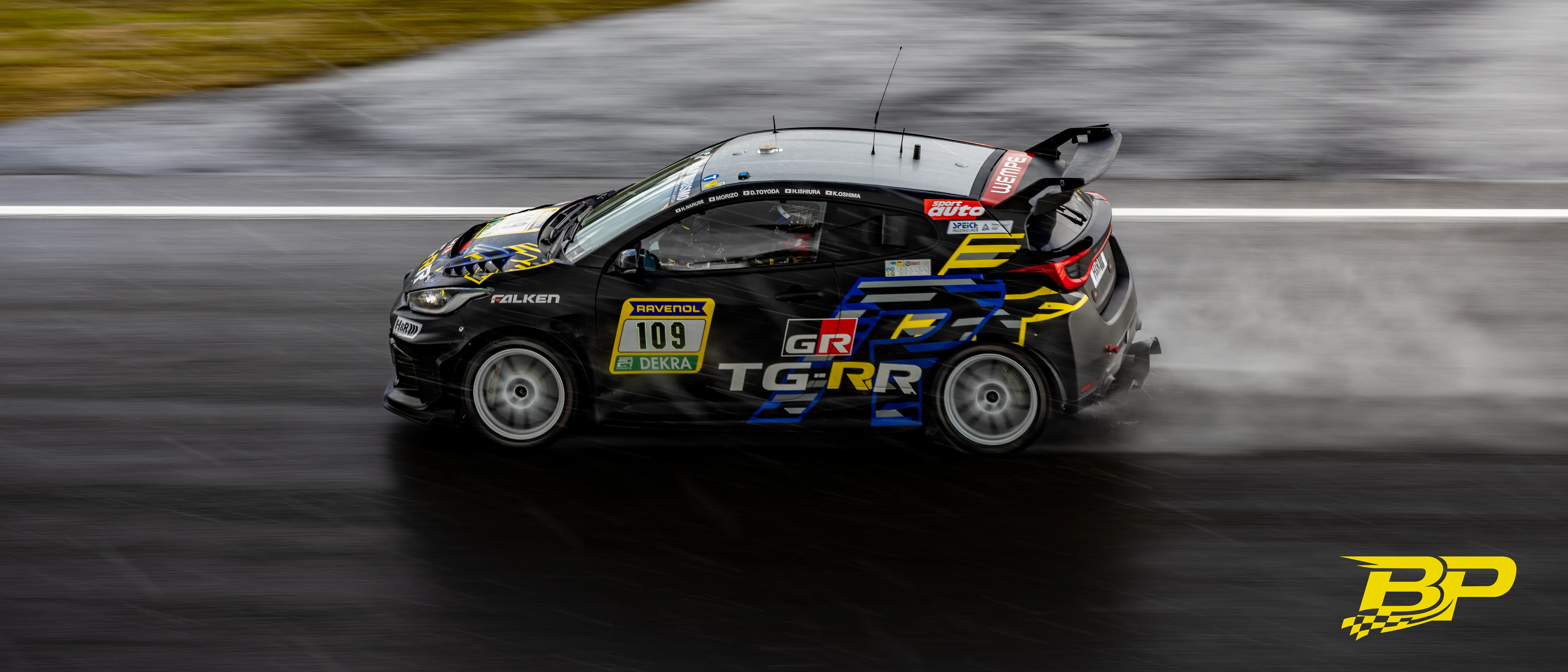 Black No. 109 touring car throwing up spray on a rain-soaked track.