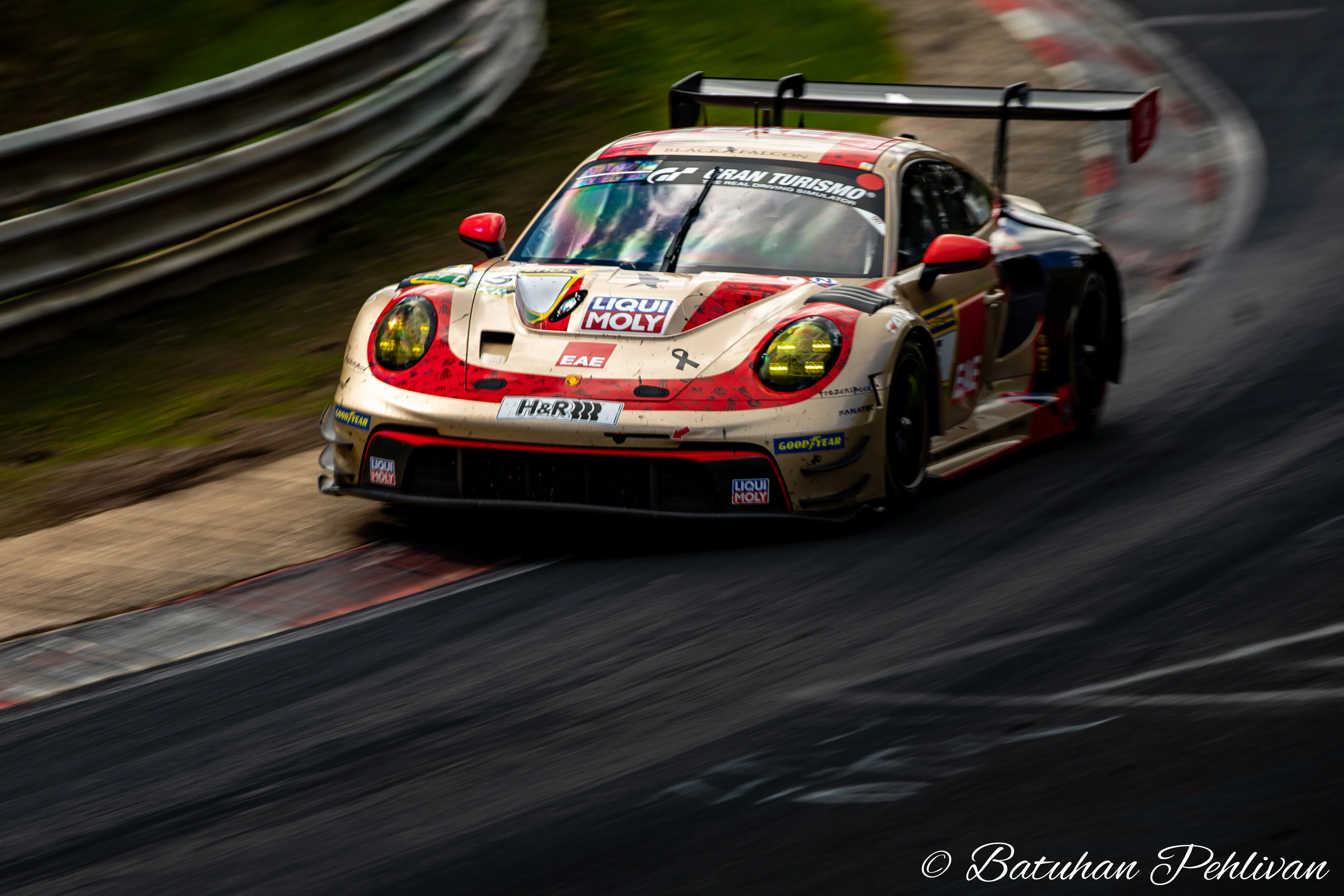 White-and-red Porsche 911 GT race car riding a red-and-white kerb.