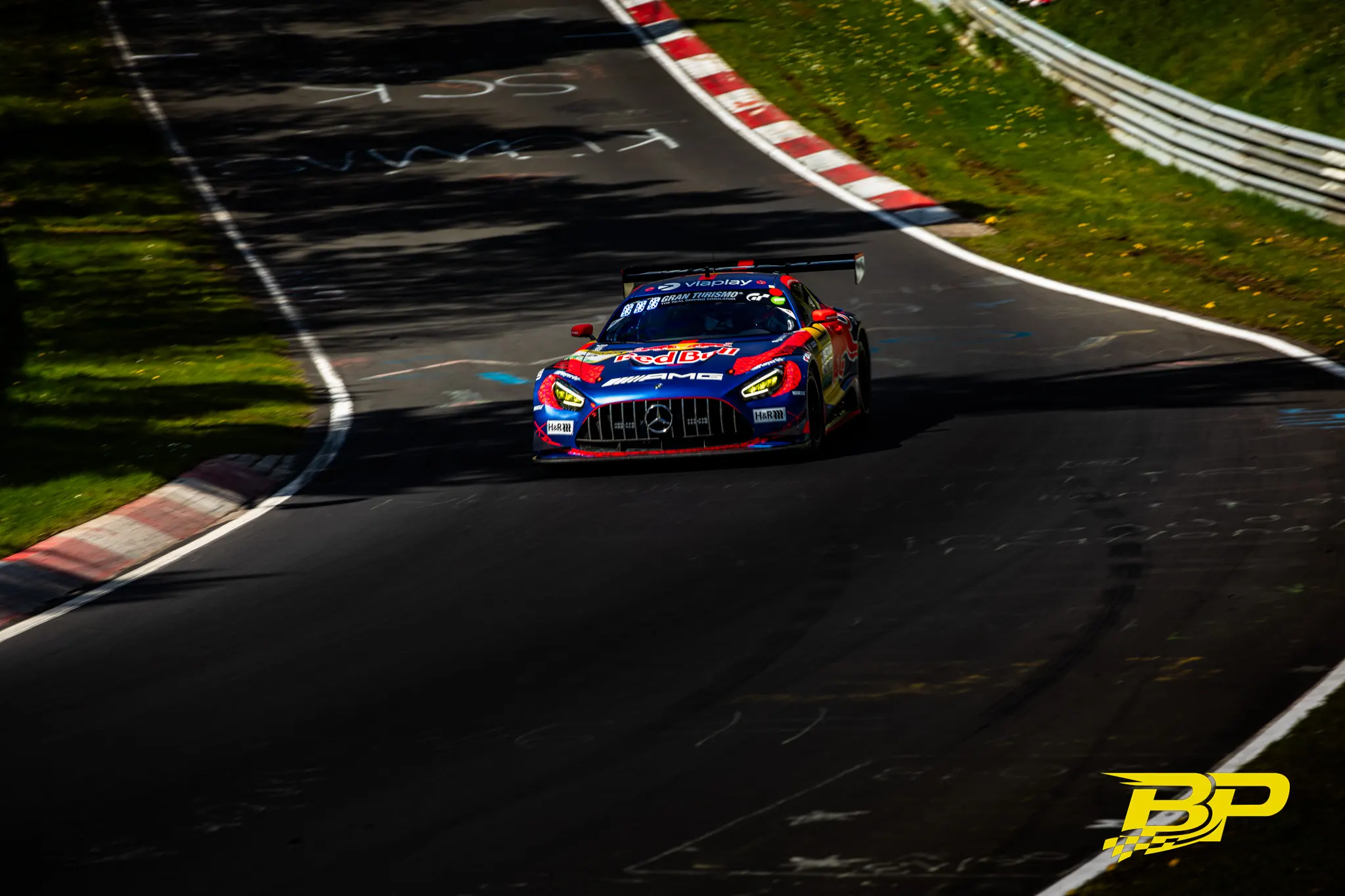 Rot-blauer Red-Bull Mercedes-AMG GT3 nähert sich in einer schattigen Nordschleifen-Kurve.