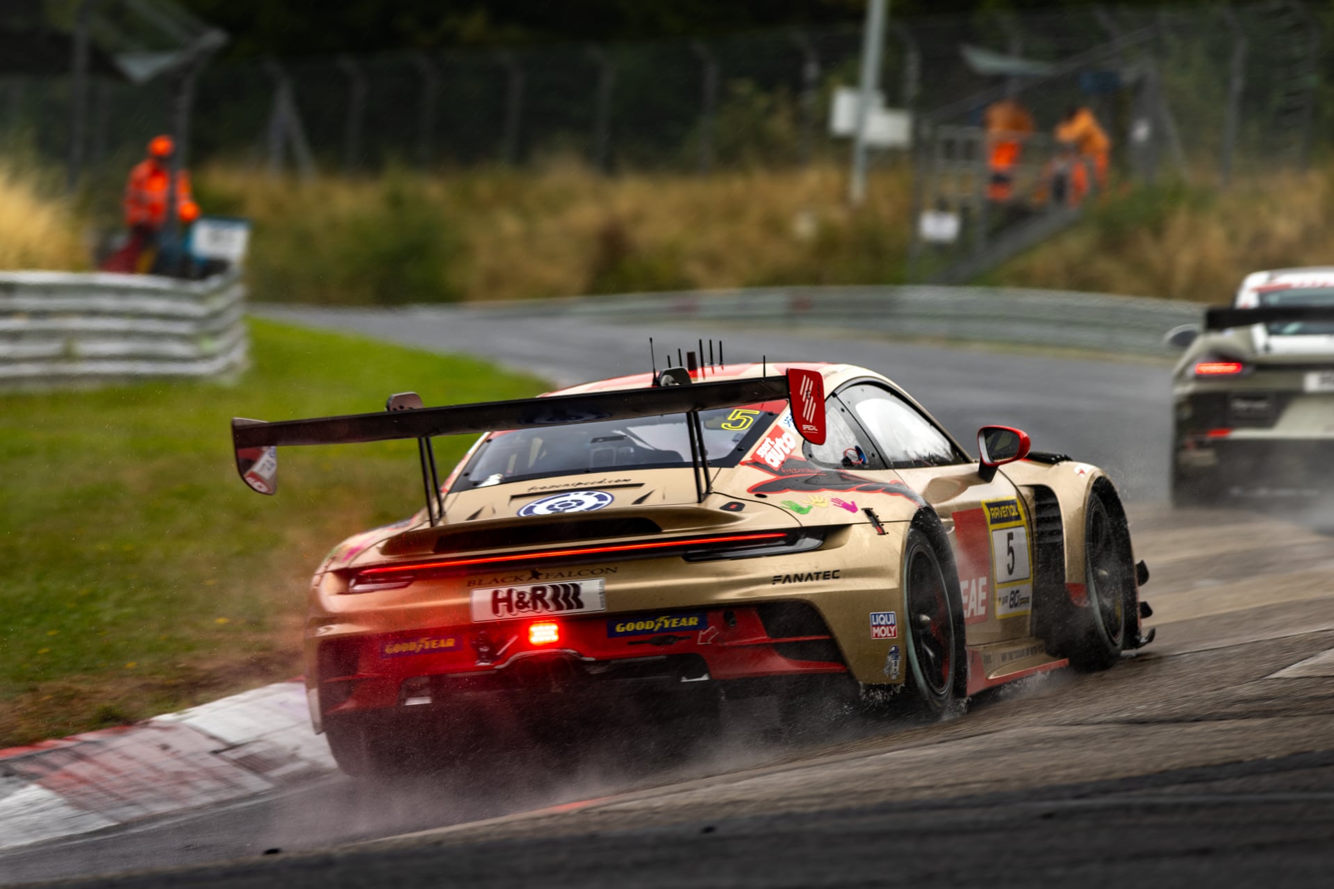 Green and black GT race car captured at speed on track during a motorsport event at the Nürburgring.