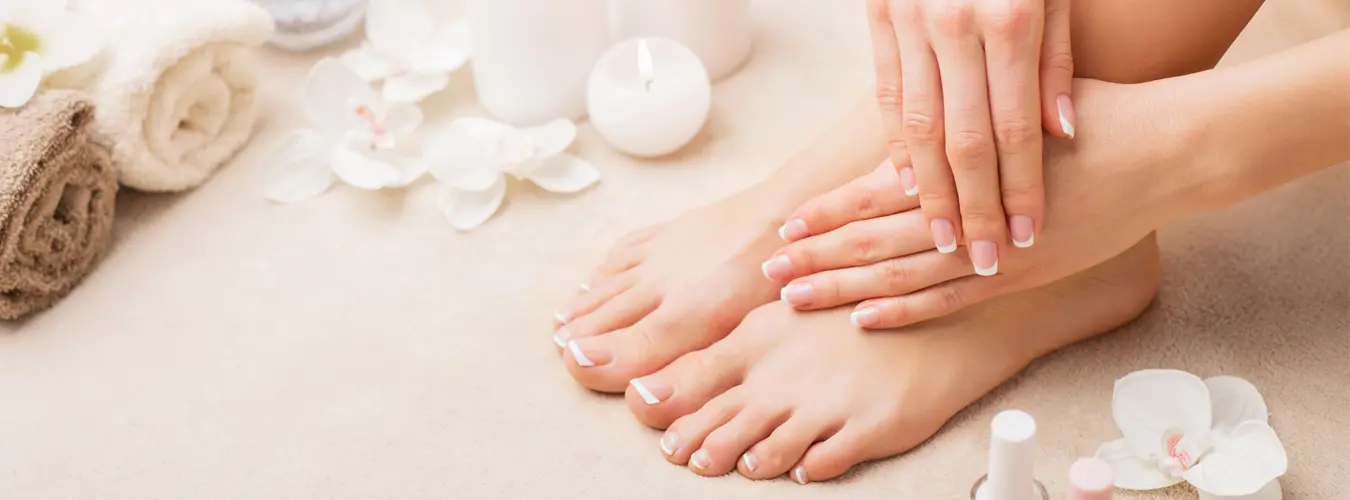 Spa scene with french manicured hands and feet, towels, and candles