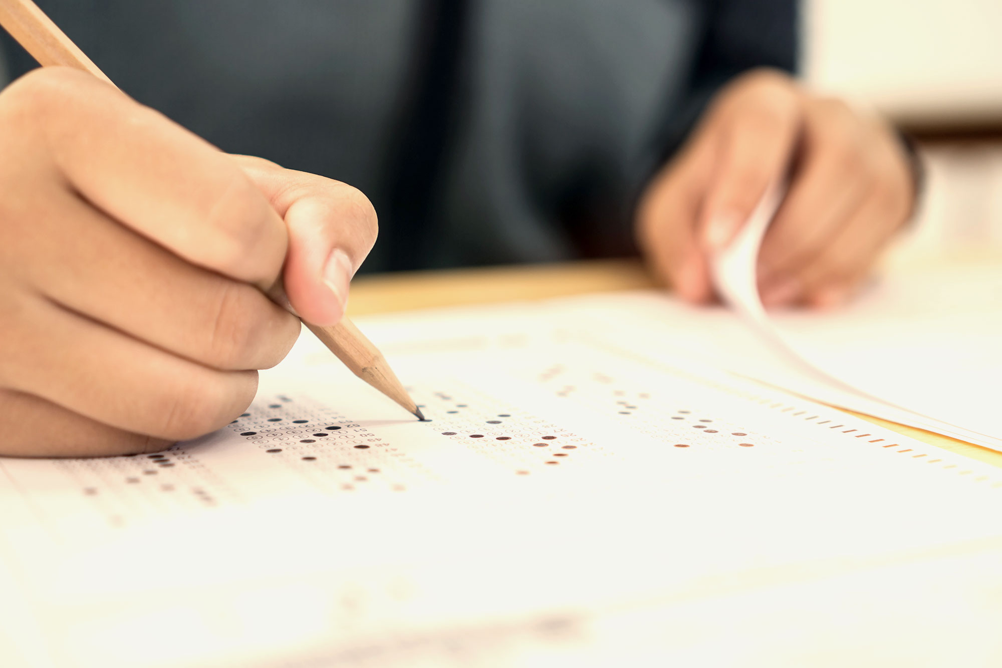 Close-up of a person filling in answers on a test with a pencil.